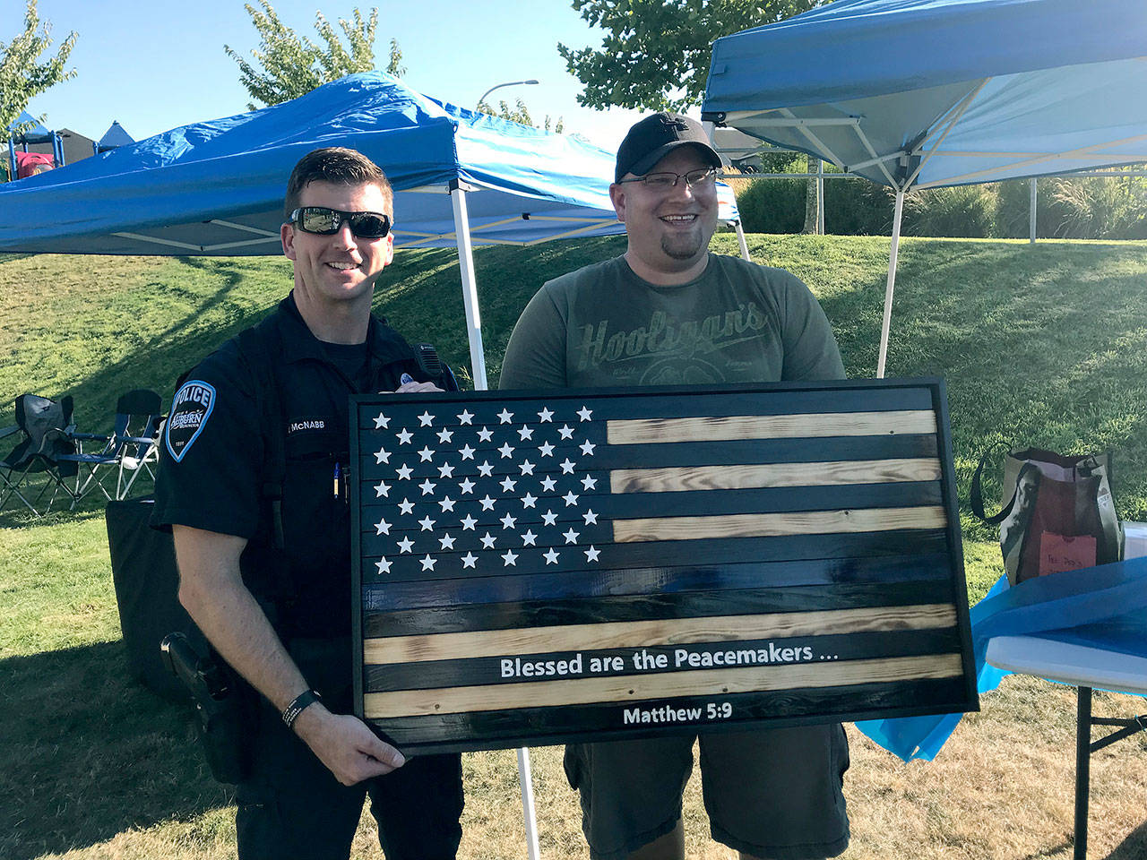 Levi Clark, right, presents a handmade U.S. flag to the Auburn Police Department as a gift of gratitude from the Edgeview community. Representing the department is Officer Mike McNabb. COURTESY PHOTO