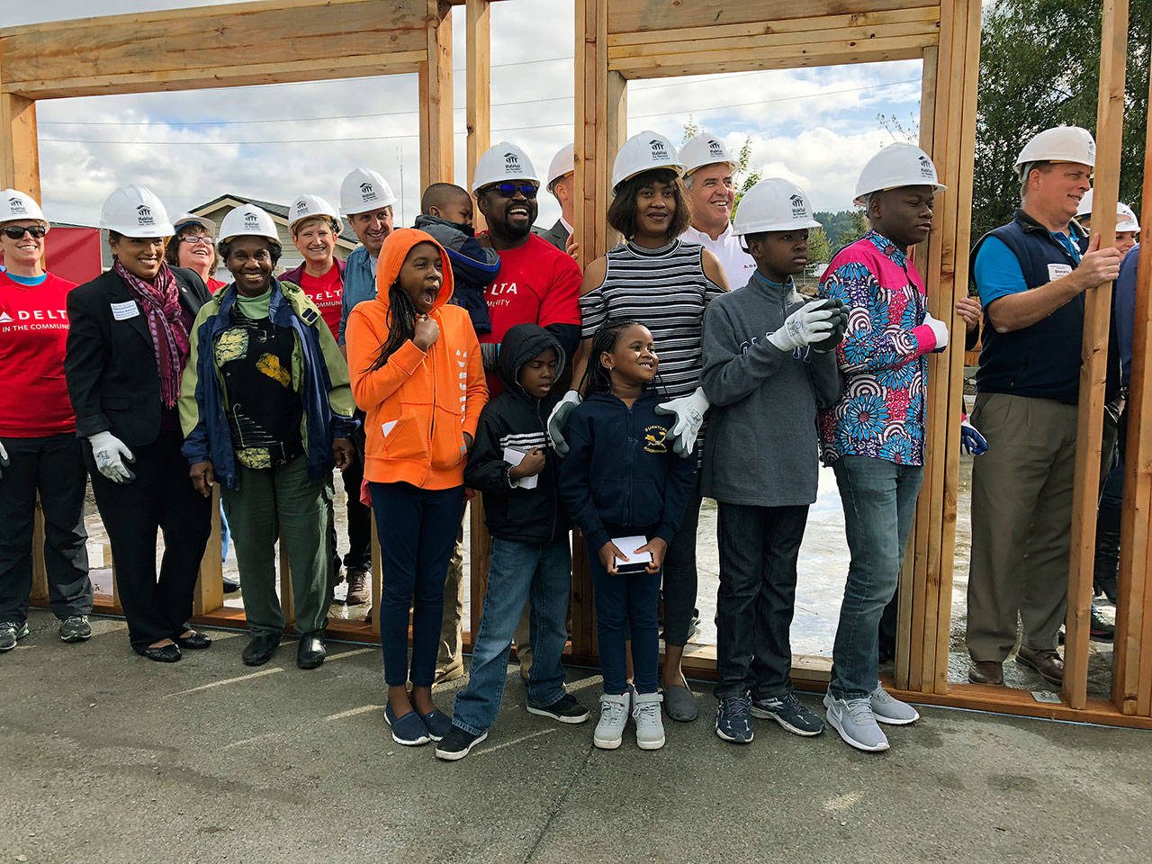 The Kayembe family joins Delta Airlines volunteers who erected a frame on the foundation of their new home in Pacific during a Habitat for Humanity Seattle-King County kickoff ceremony Sept. 11. COURTESY PHOTO