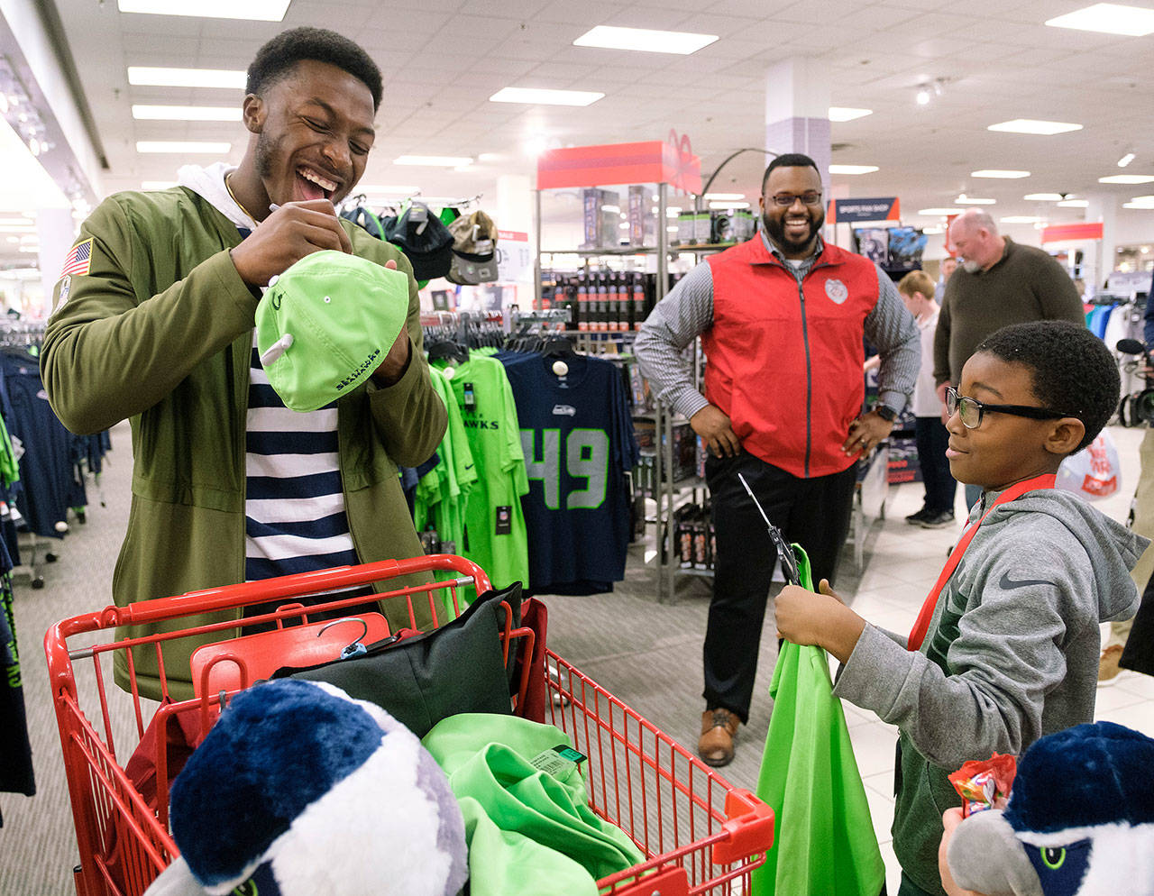 Seattle Seahawks wide receiver David Moore autographs a hat for a kid from the Auburn Valley YMCA after-school program during the JCPenney Giving Spree on Tuesday, Dec. 11 in Tukwila. In its fifth year, JCPenney is giving more than 1,200 kids a one-of-a-kind shopping experience. Stephen Brashear/AP Images for JCPenney