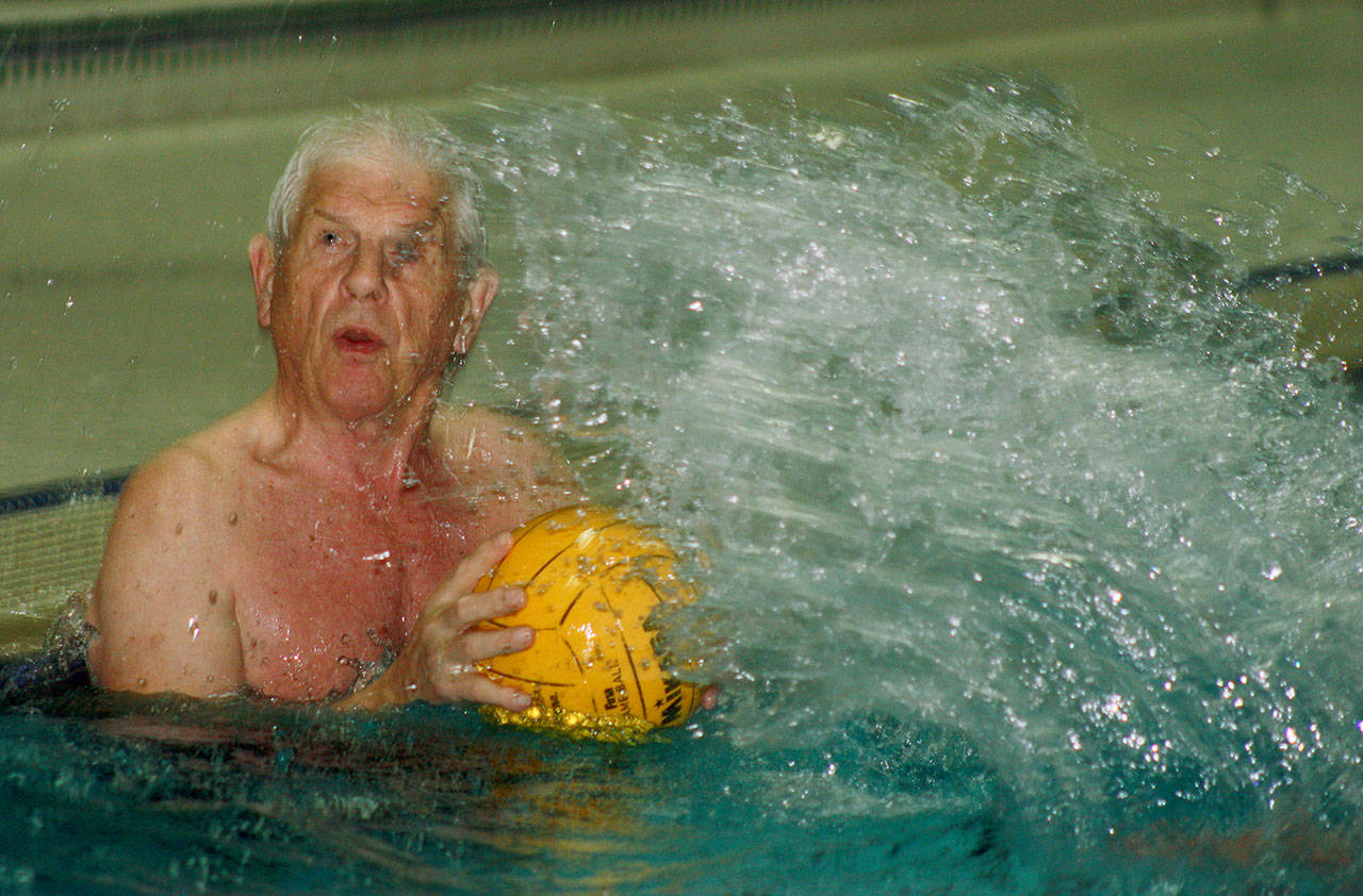Early Bird Carl Linden shoots from the baseline as the defense ruffles the waters during recent aquatic basketball play at the Auburn Valley YMCA. Linden, who turned 80 on March 13, has been a regular at the Y since 1975. MARK KLAAS, Auburn Reporter