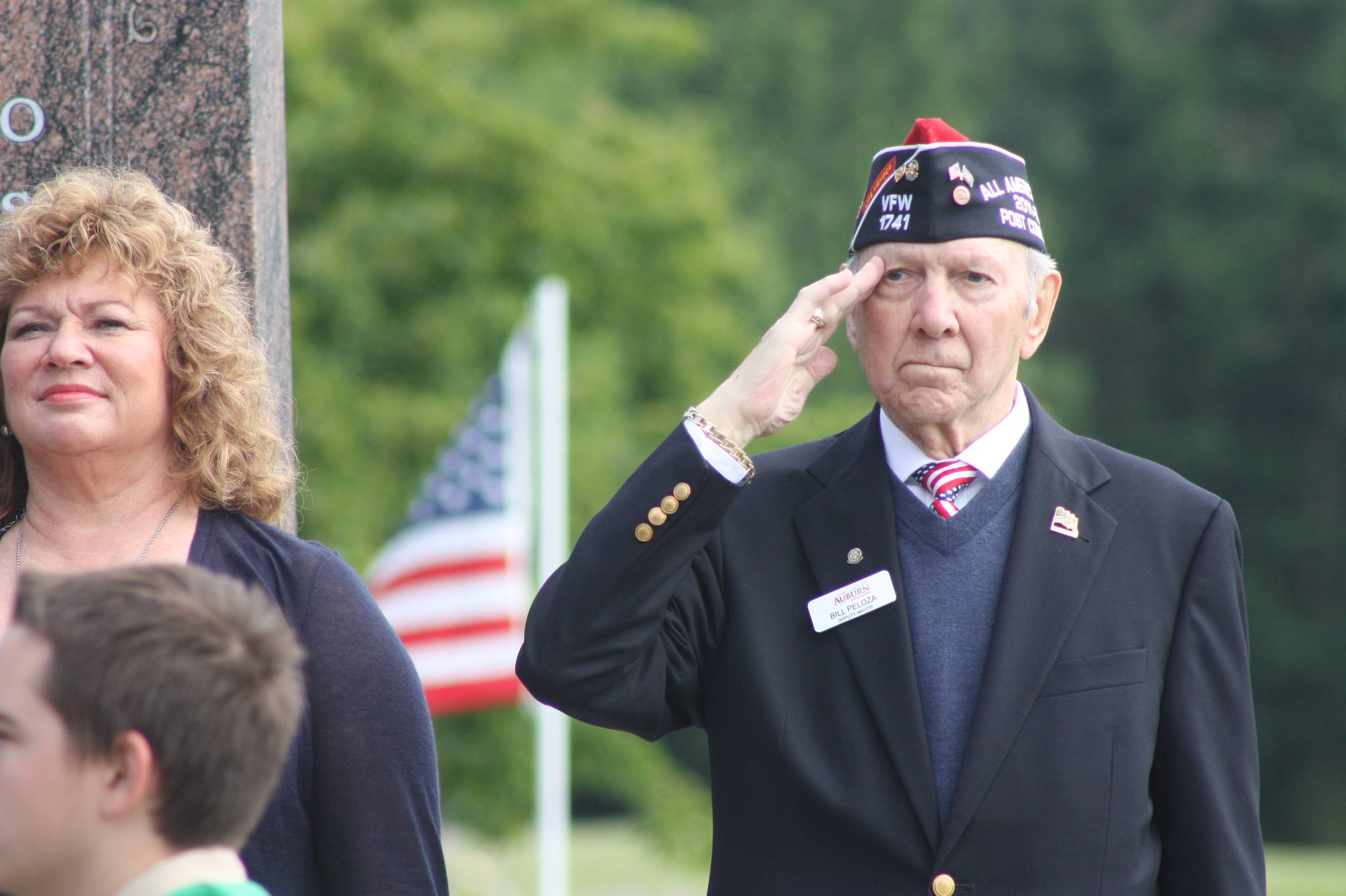 With Auburn Mayor Nancy Backus, left, Bill Peloza, deputy mayor and member of Auburn VFW Post 1741, stands and salutes the flag during the Memorial Day processional. MARK KLAAS, Auburn Reporter