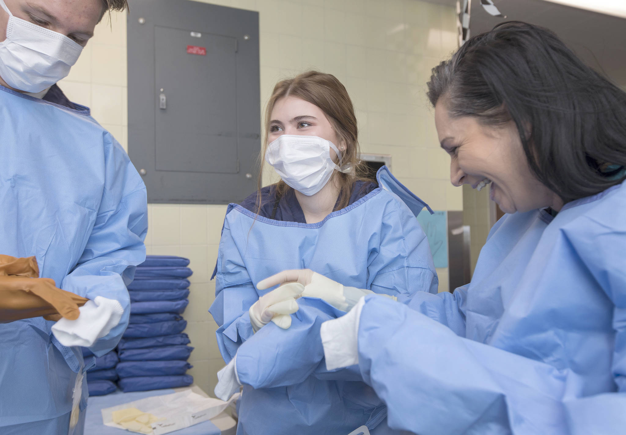 Lana Marshall, an Auburn Mountainview High School student, middle, laughs with the instructor while trying to ‘gown up’ in the emergency room unit during MultiCare’s Annual Nurse Camp at Tacoma General Hospital. COURTESY PHOTO, Patrick Hagerty