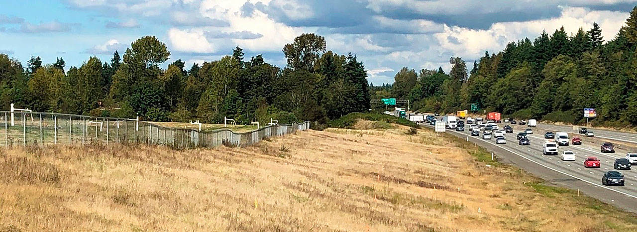 A grassy meadow covers the Midway Landfill, next to the I-5 freeway southbound lanes in Kent. White pipes behind the fence are part of the system to collect landfill gas, given off by decomposing municipal solid waste below. COURTESY PHOTO, State Ecology