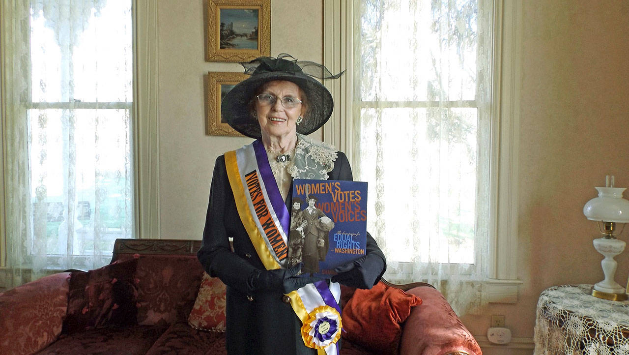 Wearing suffragist attire, Neely Mansion Association board member Hilda Meryhew displays ‘Women’s Votes, Women’s Voices,’ the book that author Shanna Stevenson will be talking about at the March 21 Bookmarks & Landmarks program at Neely Mansion. COURTESY PHOTO