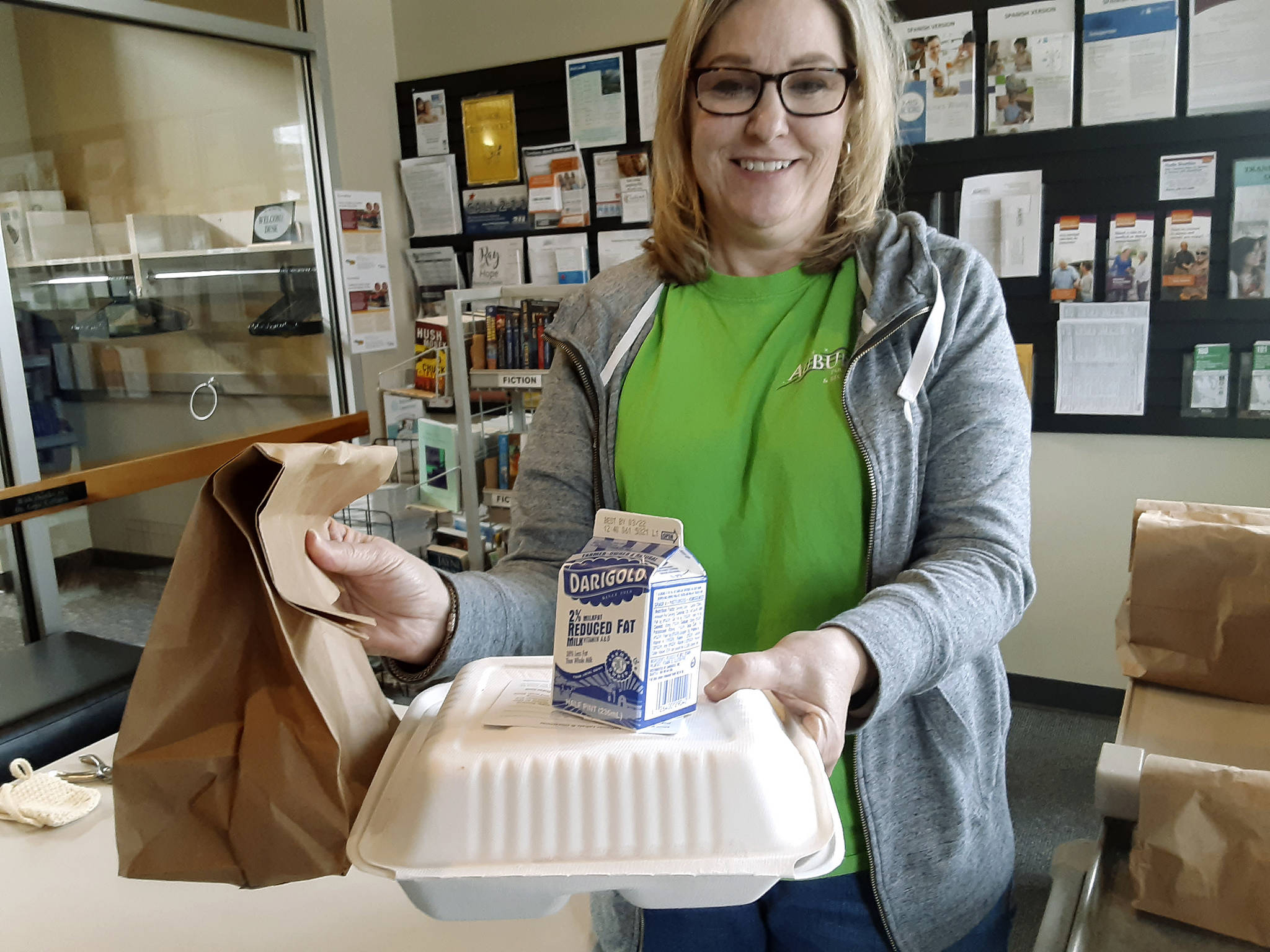 The Auburn Senior Activity Center has closed, but the meal programs roll on, says Director Radine Lozier, here with one of the lunch bags bound for seniors Tuesday afternoon. ROBERT WHALE, Auburn Reporter