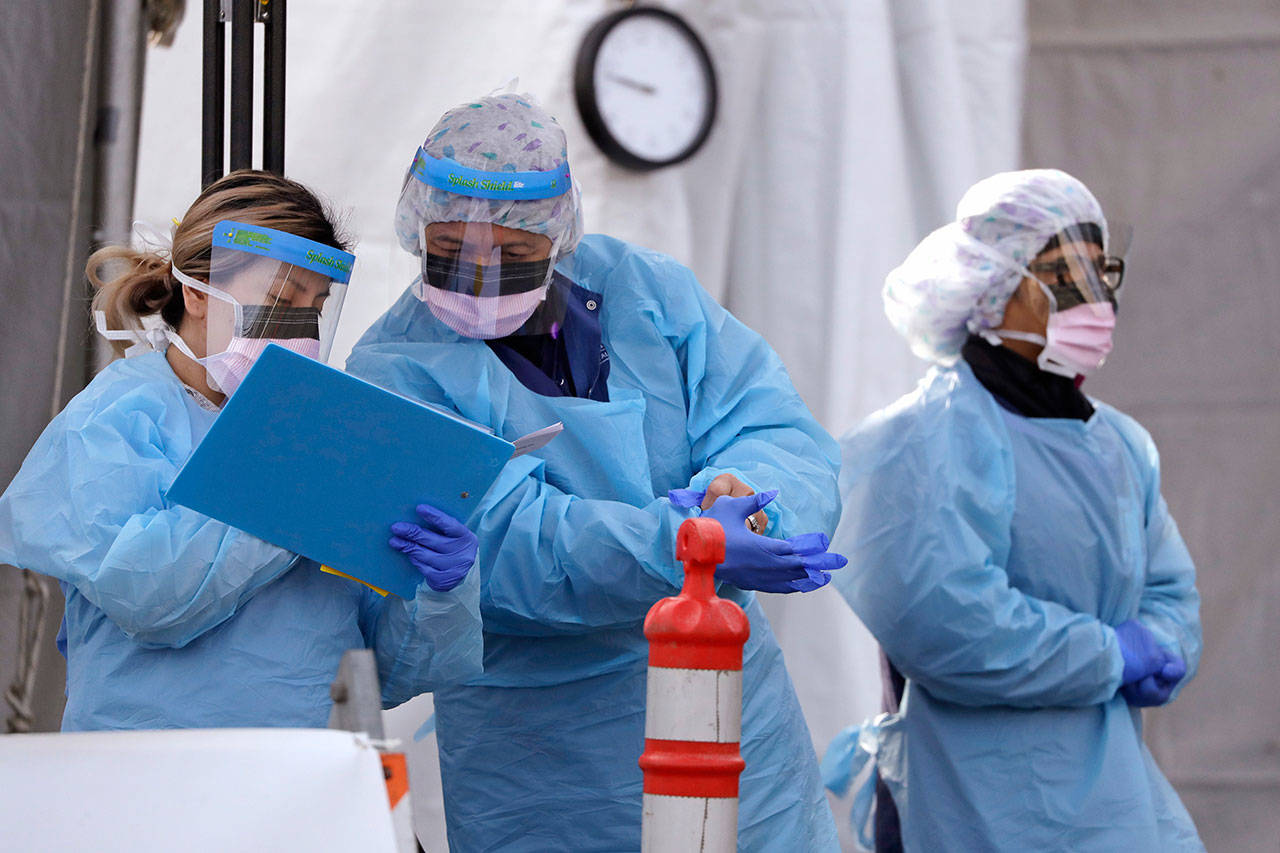 Medical personnel complete administrative work after testing a patient at a drive-through coronavirus testing station for University of Washington Medicine patients March 17 in Seattle. (AP Photo/Elaine Thompson)