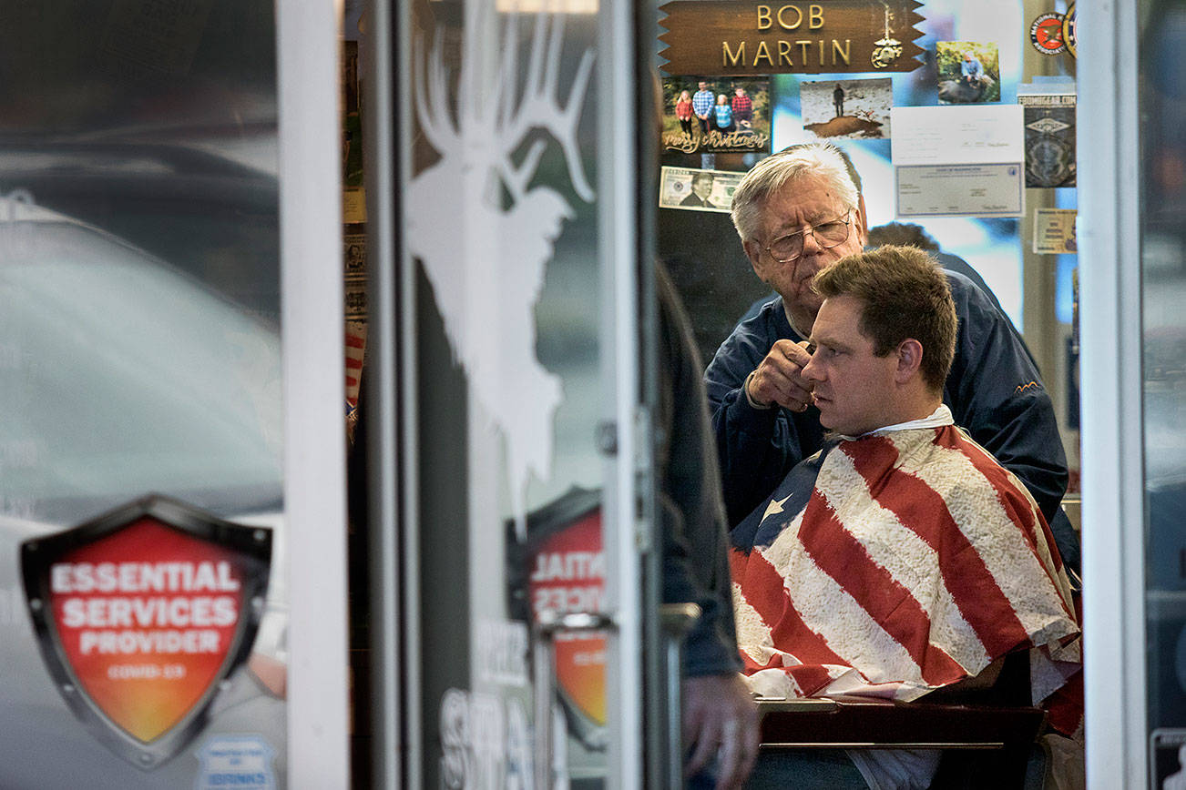In defiance of Gov. Jay Inslee’s stay-home order, owner Bob Martin cuts a customer’s hair at The Stag barbershop on Saturday, May 2, 2020, in Snohomish, Wash. Dozens of people showed up and stood in line to get a haircut. Photo by Andy Bronson/The Herald