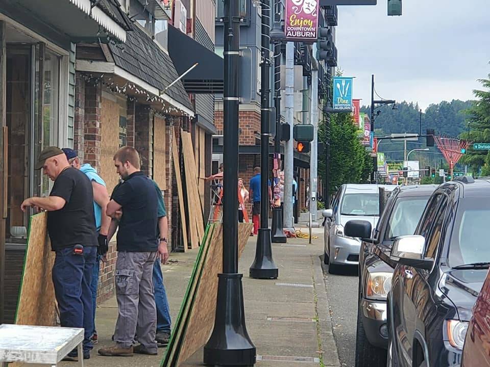 A photo posted June 3 on the Downtown Auburn Cooperative Main’s Facebook page showing volunteers installing boards over business windows.