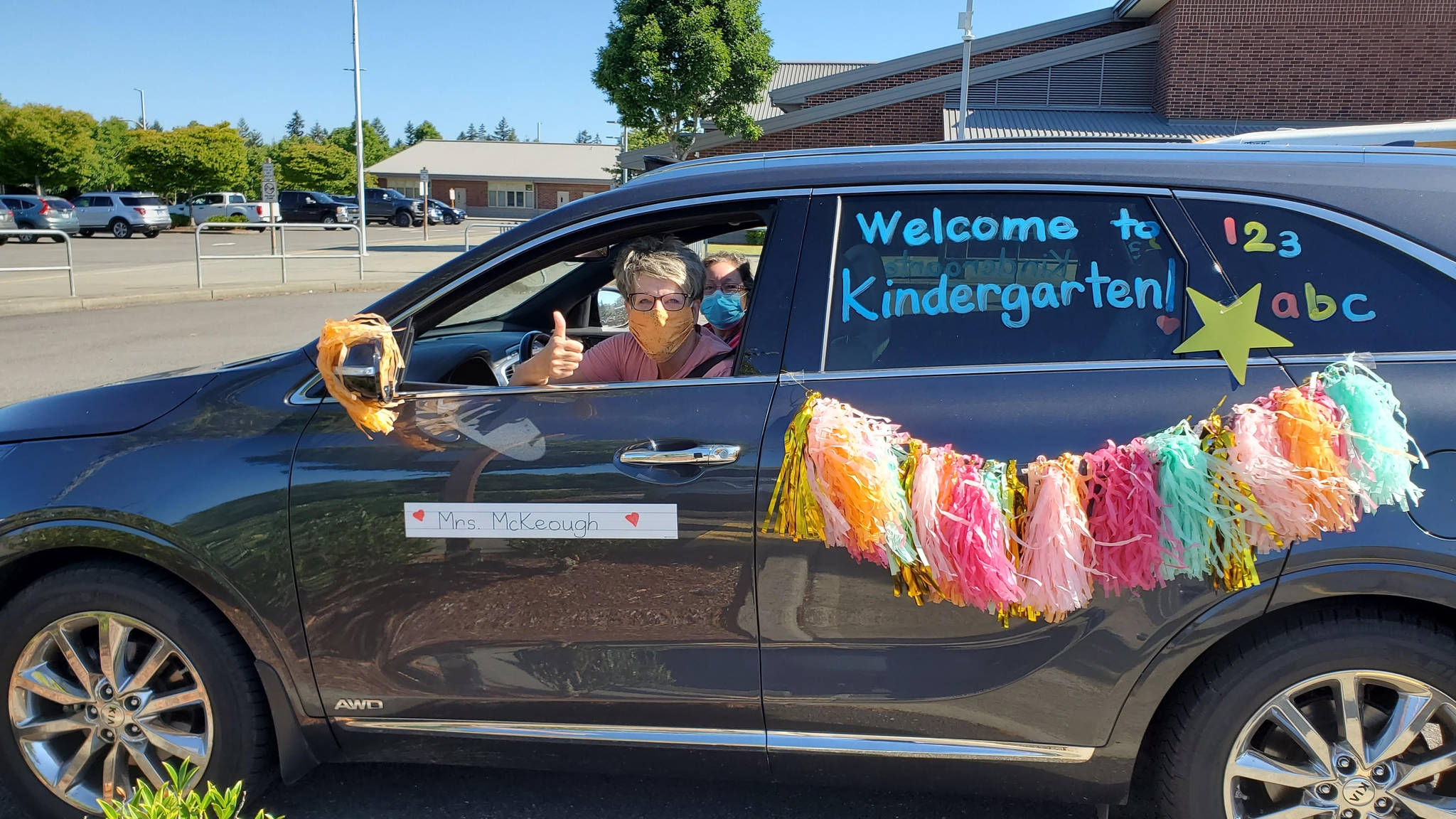 A Lakeland Hills Elementary teacher riding in the district’s car and bus parade last week signals her eagerness to welcome students to school on opening day Sept. 9. Courtesy photo