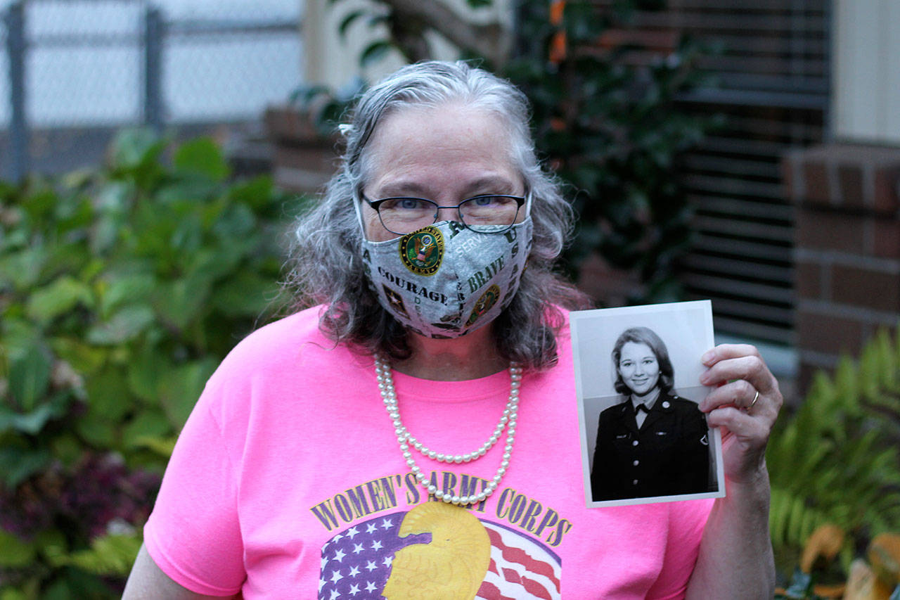 Torry Hemmert holds a photo of herself taken while she was in the army while wearing one of her handmade masks. Photo courtesy of her son, Jon Hemmert