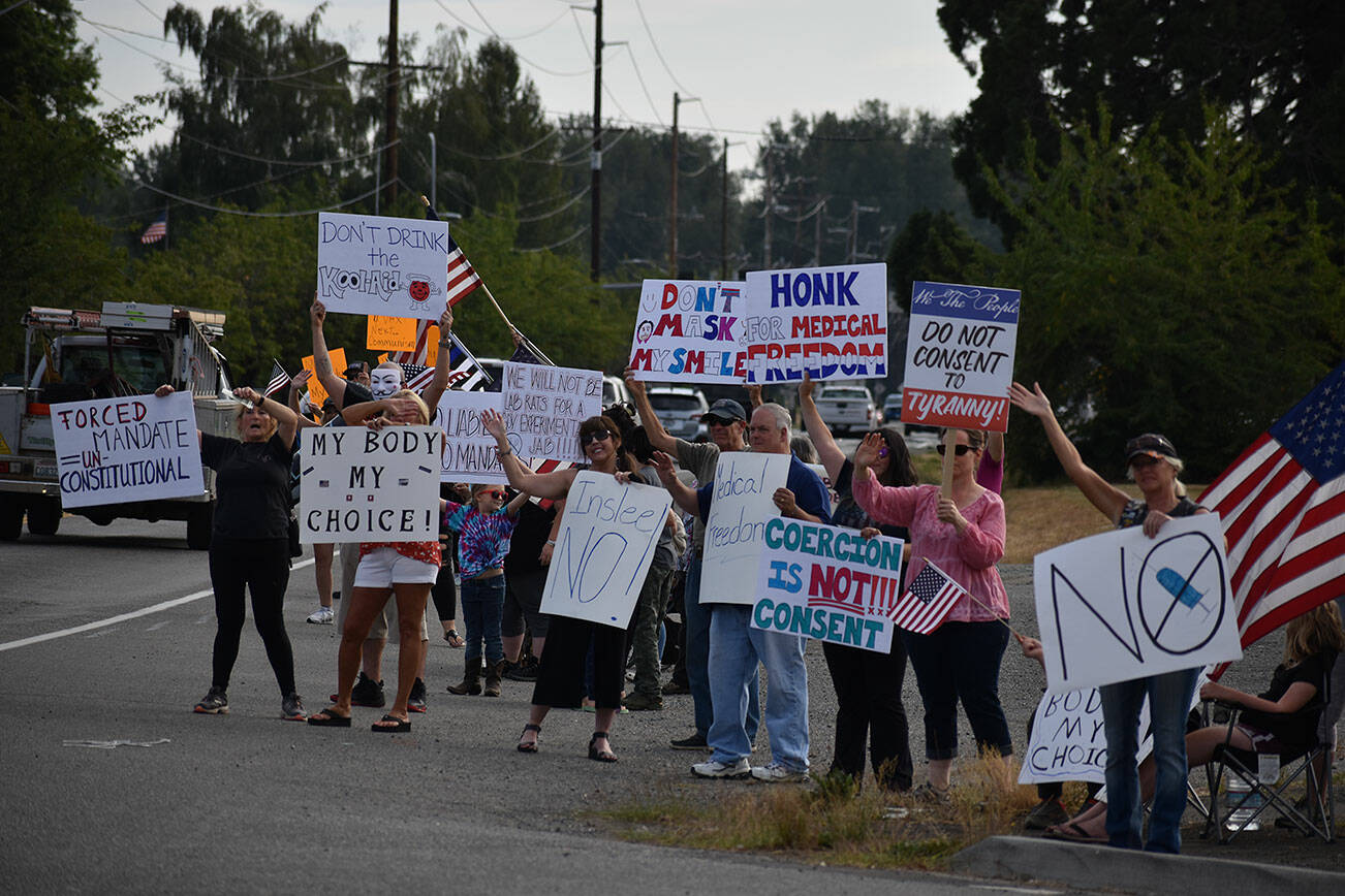 People hold up signs in protest of Gov. Jay Inslee’s latest proclamations during a Rally for Medical Freedom on Aug. 25 in Buckley. Photo by Alex Bruell/Sound Publishing