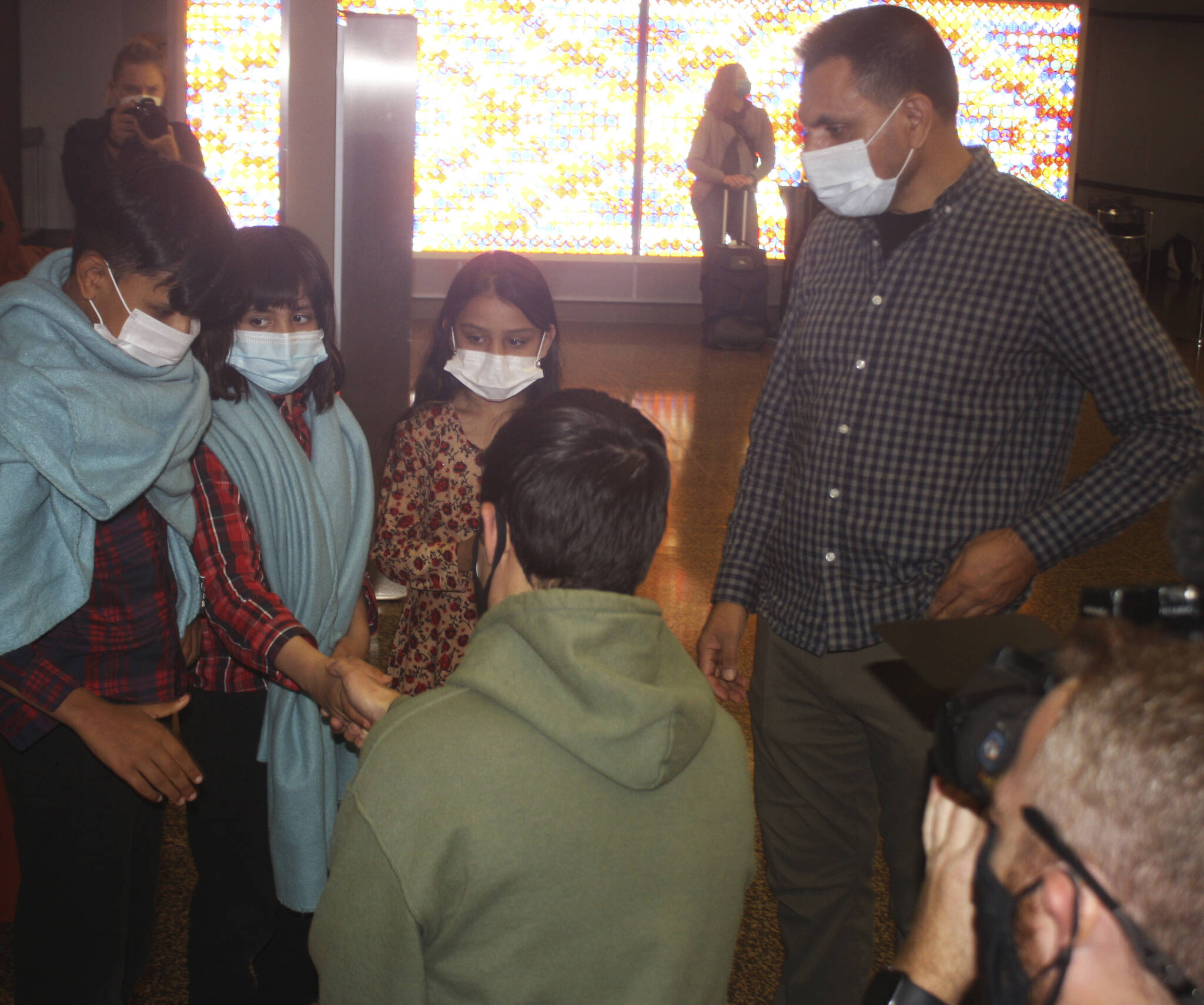 Afghan war veteran Chris Franco, center, greets the children of Azizulla Jabarkhail, right, on Oct. 1 at Sea-Tac Airport after their return home with their mother to Kent from Afghanistan. STEVE HUNTER, Kent Reporter