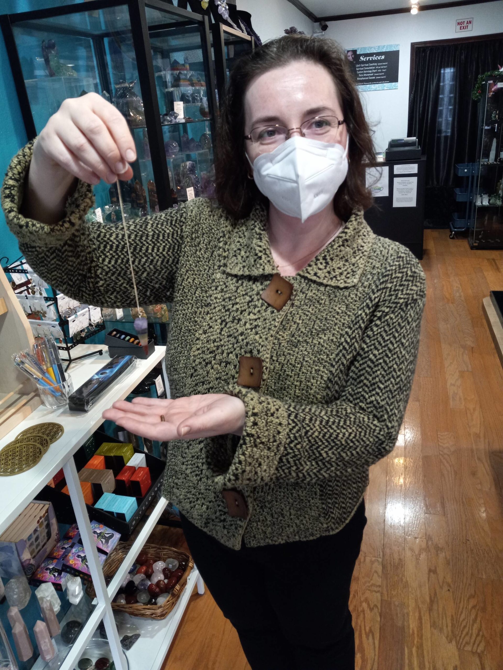 Juliana Solovjev, co-owner of Aura Song Gifts, demonstrates the use of a pendulum, one of the metaphysical “tools” available at her boutique. Photo by Robert Whale, Auburn Reporter