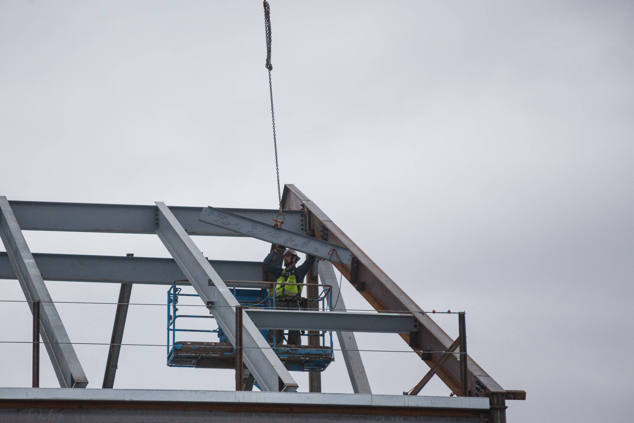 An iron worker installs the final steel beam in the new Lea Hill Elementary School. Photo by Henry Stewart-Wood/Sound Publishing