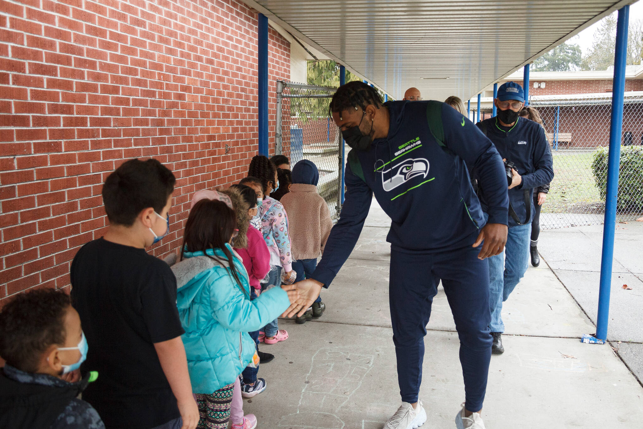 Photo by Henry-Stewart-Wood
Seahawks linebacker Jordyn Brooks high-fives kids at Chinook Elementary School on their way to class on Tuesday, Mar. 8, 2022.