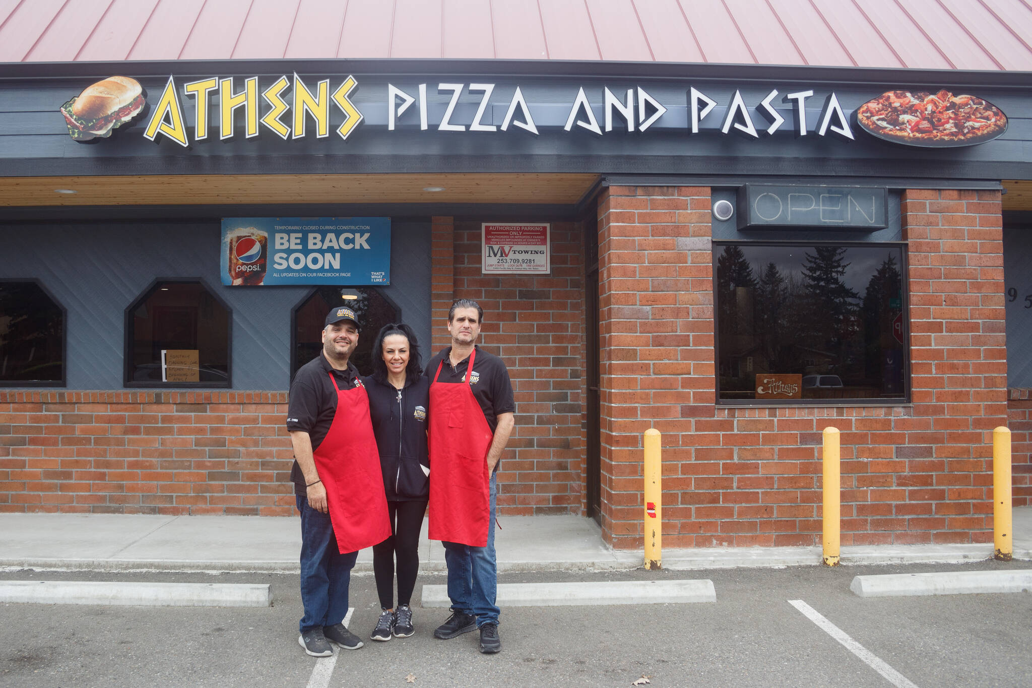 (Left to right) Bill, Nina and Tom Contoravdis, co-owners of Athens Pizza and Pasta, pose for a photo in front of their restaurant that is set to re-open for take-out on Friday, April 1. Photo by Henry Stewart-Wood/Sound Publishing
