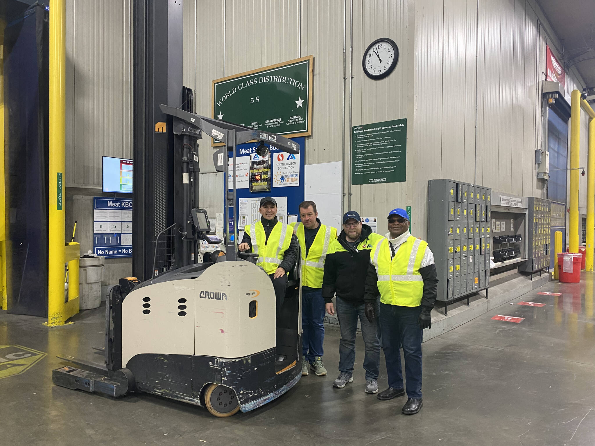 (Left to right) Sergey Alter poses on a forklift with Travis Parke, Seth Myers and Joe Drake at the Safeway distribution center where Alter works. Photo by Henry Stewart-Wood/Sound Publishing