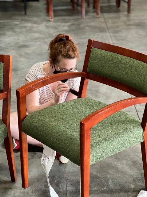 Sarah Berkley repainting a chair at the Furniture Fix-it Fair. Photo courtesy of Xenia Dolovova.