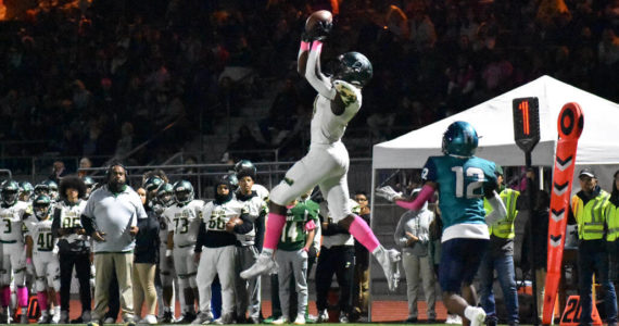 Auburn High School’s Lukens Valcin reaches up high to reel in a pass from Amari Goodfellow on Oct. 28 against Auburn Riverside. Photo by Ben Ray/Sound Publishing