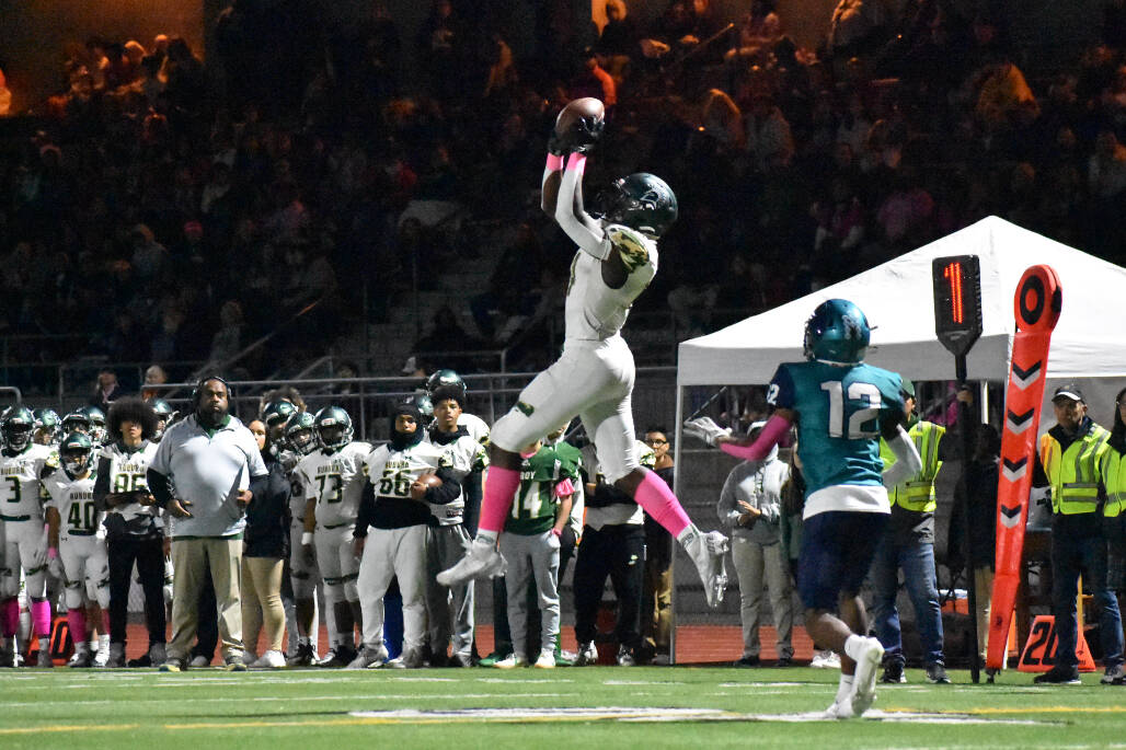 Auburn High School’s Lukens Valcin reaches up high to reel in a pass from Amari Goodfellow on Oct. 28 against Auburn Riverside. Photo by Ben Ray/Sound Publishing