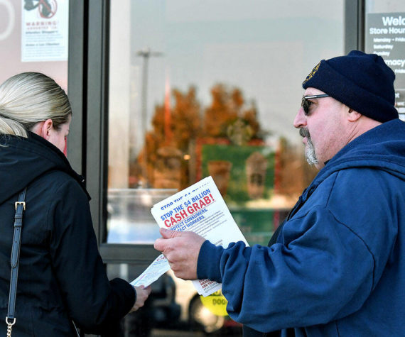 Kevin Flynn, right, a meat-cutter with the Marysville Albertsons, hands a leaflet to a shopper during an informational campaign on Wednesday, Nov. 9, 2022. Flynn was one of about a dozen grocery store workers handing out leaflets to shoppers about the proposed merger between Albertsons and Kroger. (Mike Henneke / The Herald)