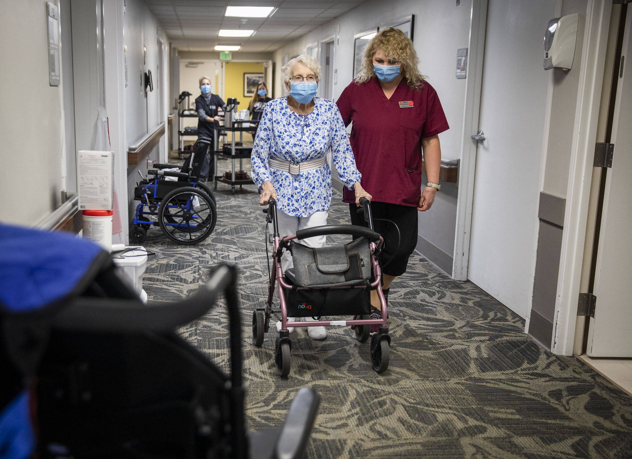 CNA Nina Prigodich, right, goes through restorative exercises with long term care patient Betty Long, 86, at View Ridge Care Center on Friday, in Everett. (Olivia Vanni / The Herald)