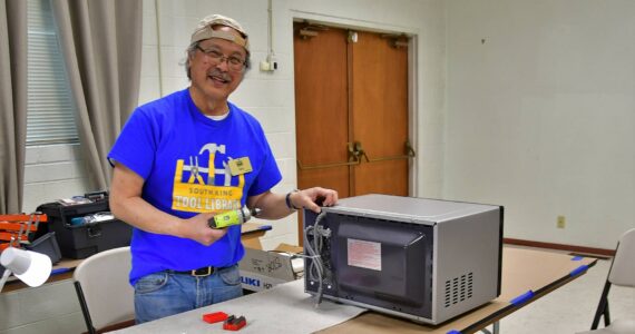 Gary Ichinaga, a volunteer fixer at the South King Tool Library, works on a microwave during last week’s repair cafe, an event in which locals can get help repairing their stuff rather than throwing it away. Photo by Bruce Honda.