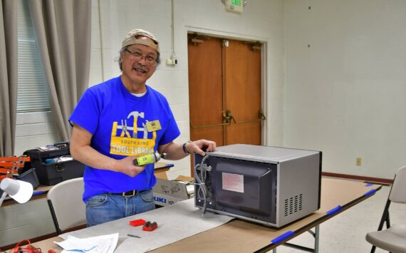 Gary Ichinaga, a volunteer fixer at the South King Tool Library, works on a microwave during last week’s repair cafe, an event in which locals can get help repairing their stuff rather than throwing it away. Photo by Bruce Honda.