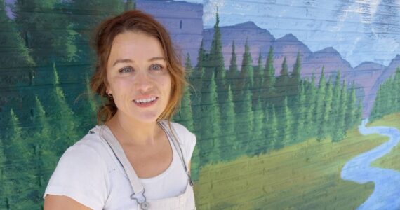 Cody Esp in front of the mural she is painting on the building at East Main and 2 Auburn Way North. Photo by Robert Whale, Auburn Reporter.