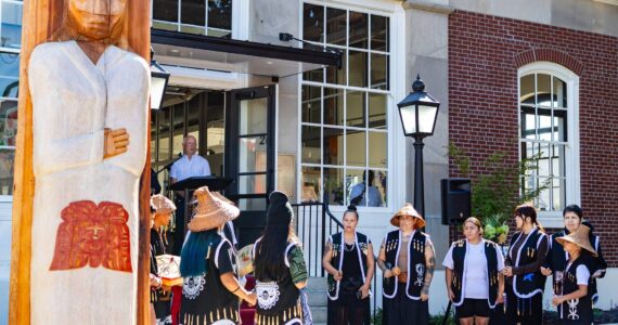 The Muckleshoot Indian Tribe unveil their gift of a Welcome Figure and provide a song and blessing during the Postmark Center for the Arts grand opening. The figure was created by Muckleshoot artists Sam Obrovac, Tyson Simmons and Keith Stevenson. Photo courtesy of City of Auburn