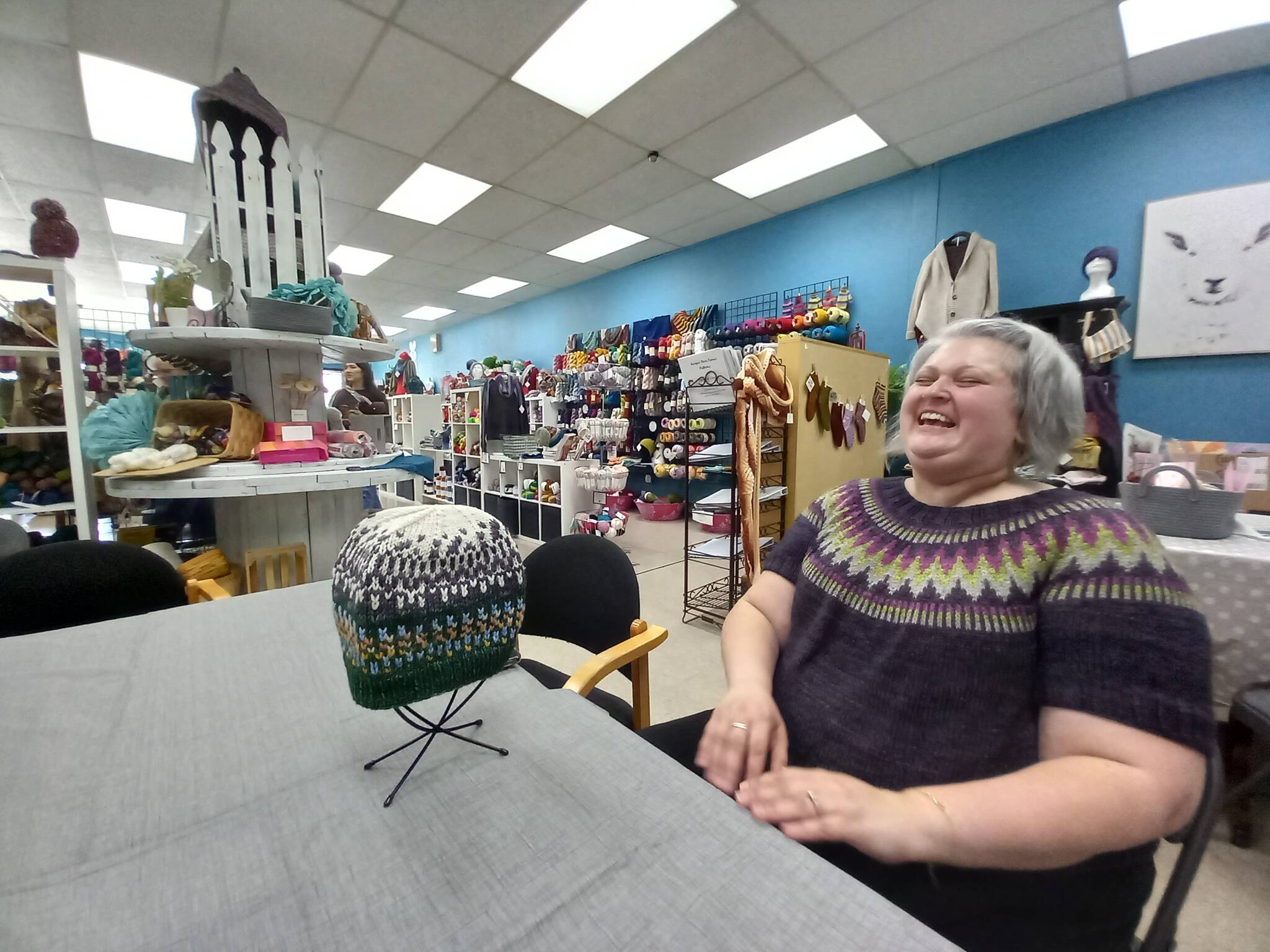 Jen Reeves, wearing a sweater she has woven, throws herself back in a chair to indulge in one of her favorite activities, laughter, at her yarn shop Little Knittym at the corner of East Main and Auburn Avenue. Photo by Robert Whale, Auburn Reporter.