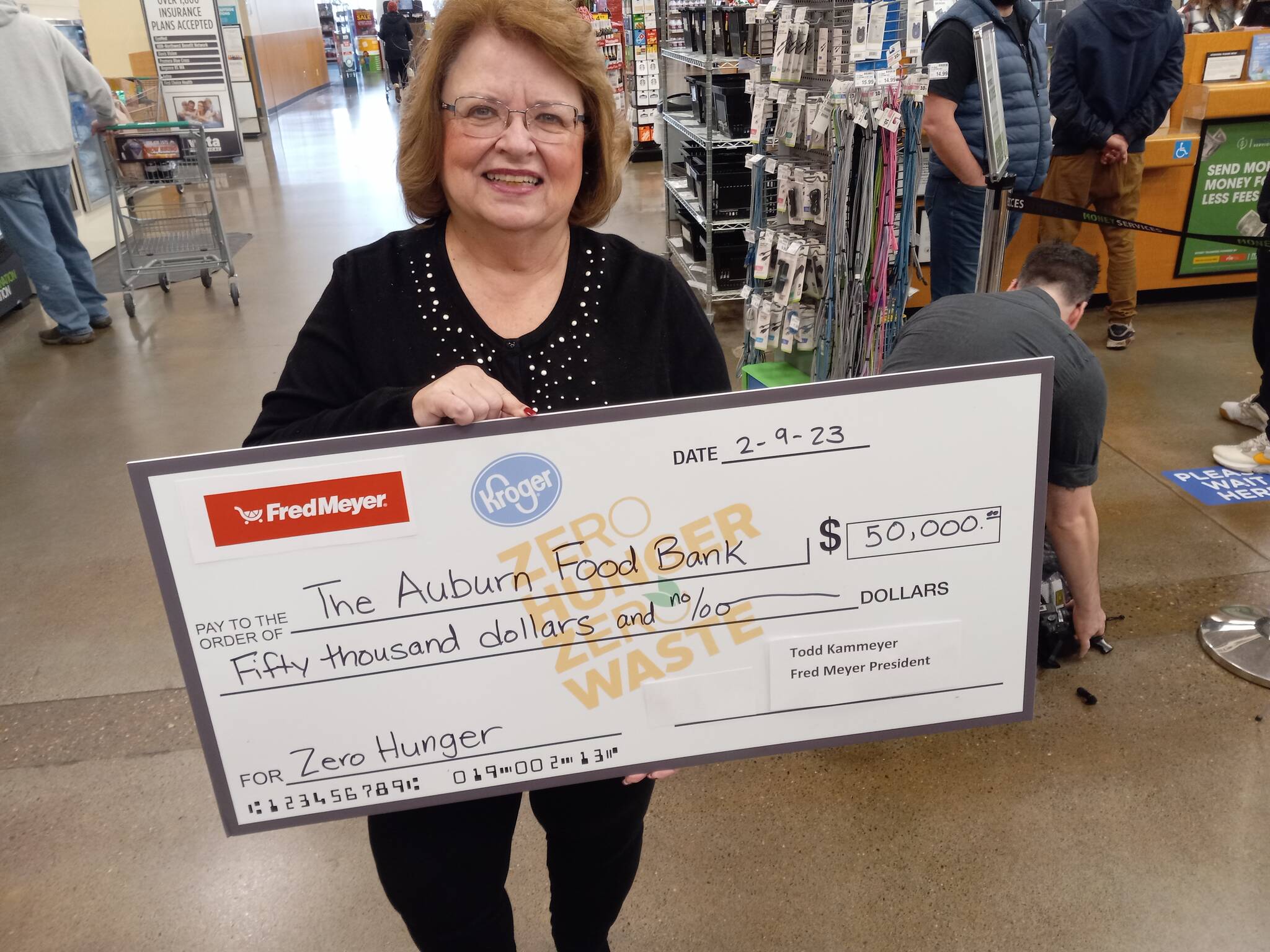 Auburn Food Bank director Debbie Christian is all smiles as she holds a replica of the $50,000 check given to the Auburn Food Bank by the Auburn Fred Meyer store. It was the store’s entire bonus from the Washington State Lottery for selling the winning ticket in the recent Powerball jackpot. Photo by Robert Whale, Auburn Reporter.