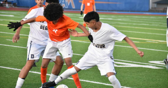 Benjamin Yitbarek battles two Decatur players for the ball. Ben Ray / The Reporter