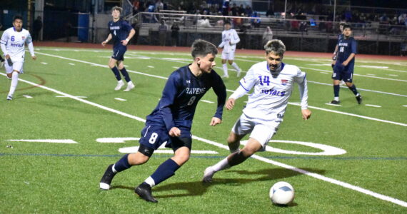 Auburn Riverside’s Luke Sullivan looks to control the ball and find a teammate with a defender closing in. Ben Ray / The Reporter