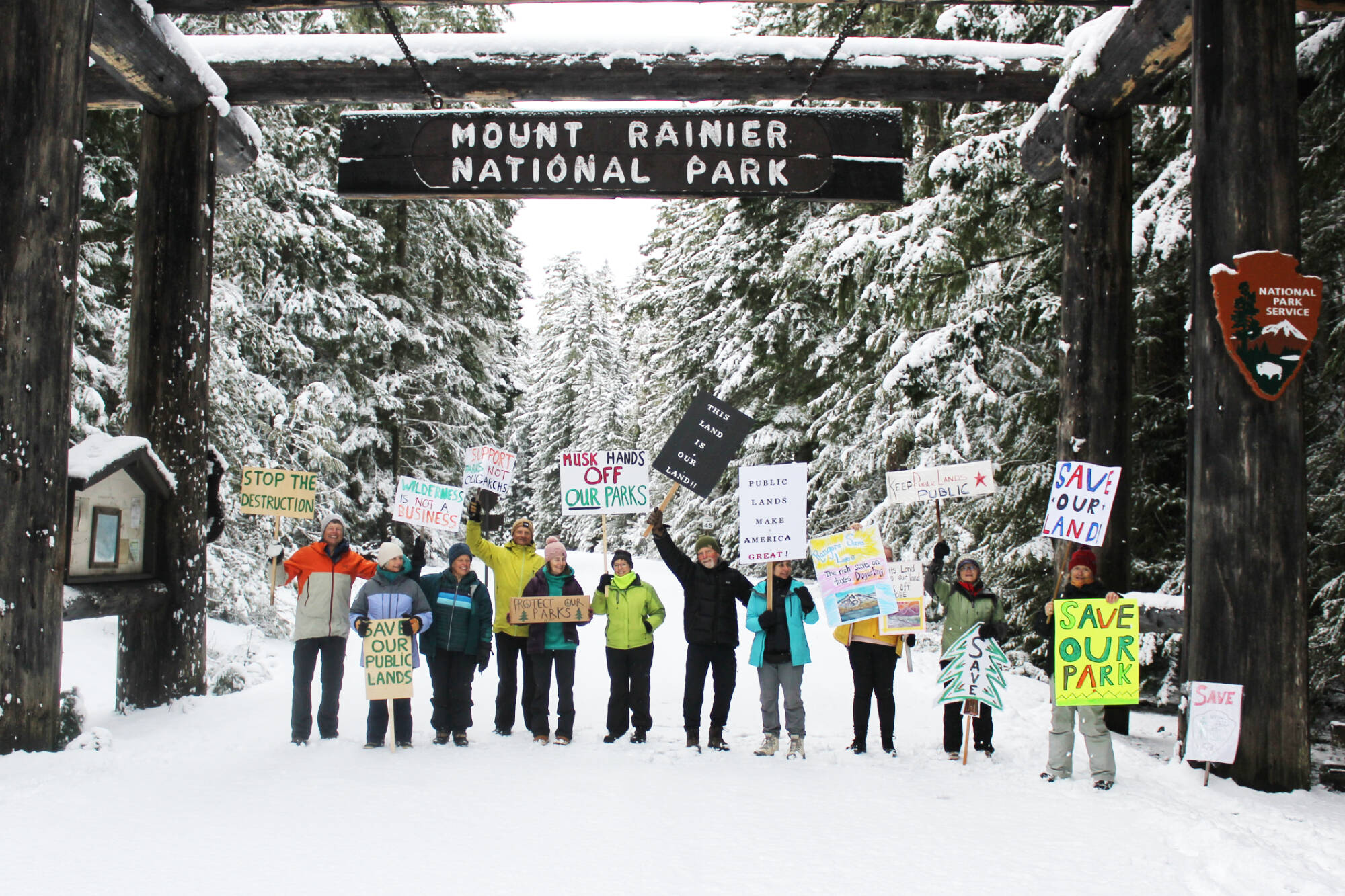 Eleven demonstrators cheered for the Forest Service and National Park Service under the entrance to Mount Rainier National Park last Saturday. All were local volunteers, and many said they hike Plateau trails often, if not every day. Photos by Ray Miller-Still