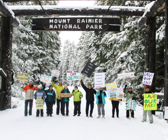 Eleven demonstrators cheered for the Forest Service and National Park Service under the enterence to Mount Rainier National Park last Saturday. All were local volunteers, and many said they hike local trails often, if not every day. Photos by Ray Miller-Still