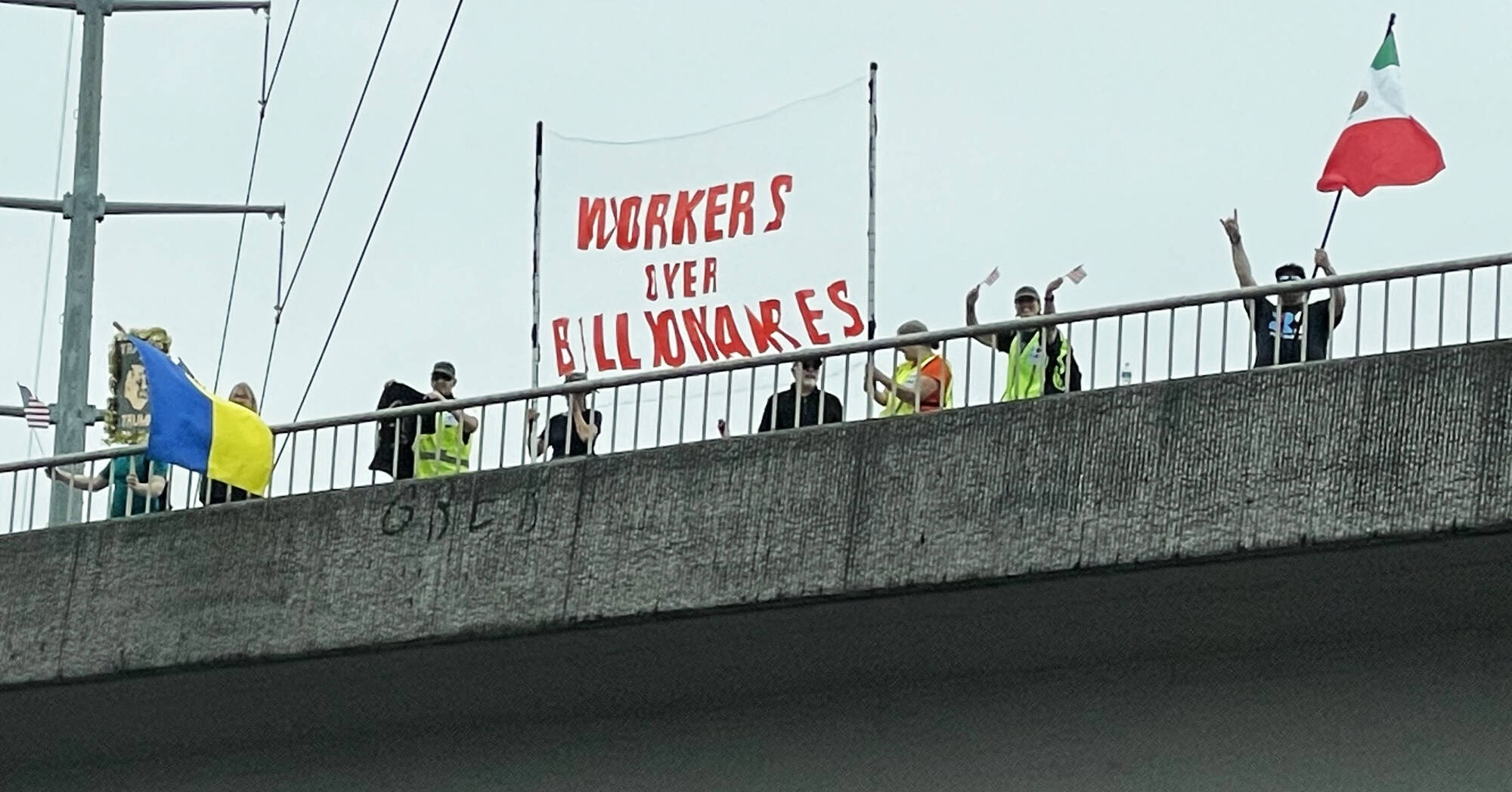 People display a banner Sept. 1 on an overpass above State Route 18 in Covington. COURTESY PHOTO, Indivisible Covington WA