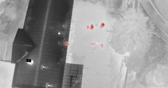 Drone thermal footage depicting the suspect sitting on the edge of the roof. Screenshot of Auburn police video.