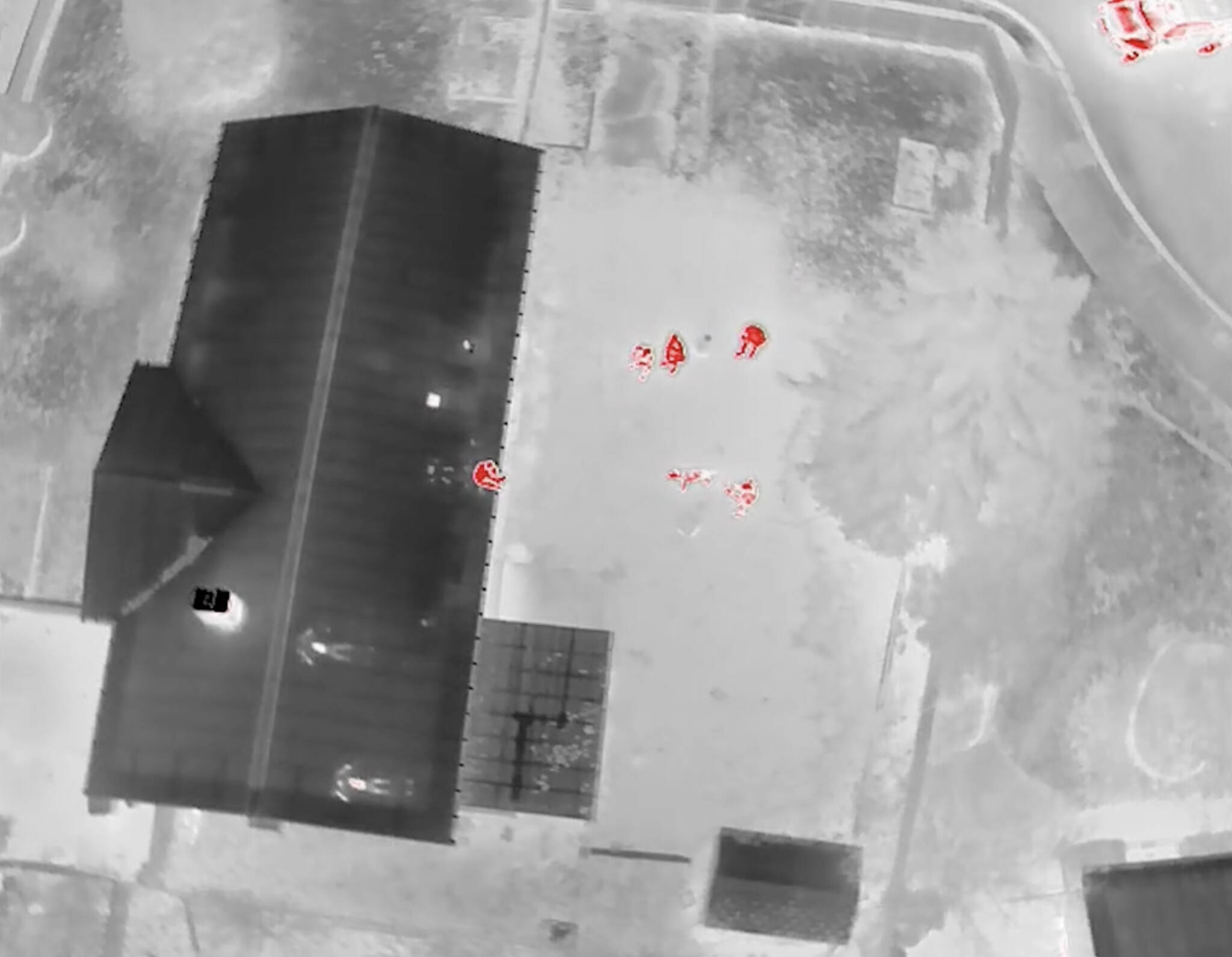 Drone thermal footage depicting the suspect sitting on the edge of the roof. Screenshot of Auburn police video.