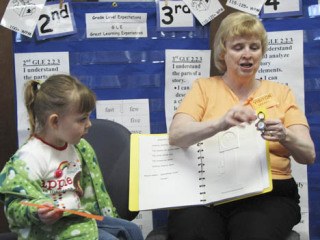 Becky Sherman shows her special wrist watch designed with Braille to a class during her visit to Lea Hill Elementary School.  She was joined by her 3-year-old granddaughter