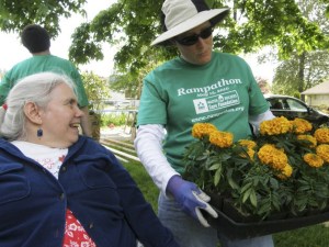 Volunteer Kelli Henderson shows Jeannie Buser a case of flowers to be planted in her Auburn yard during last weekend’s Rampathon project.