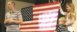 Marine Cpl. Josh Hileman presents a U.S. flag to Valley Christian School students. The flag flew with his unit in Afghanistan. With Hileman is his son