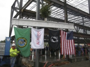 Construction workers prepare to hoist the final steel beam to the three-story Auburn Professional Plaza downtown. Atop the beam is a small evergreen