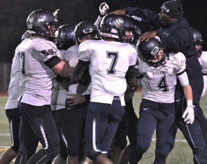 Auburn Riverside coach Bryant Thomas joins his players in celebration after the playoff-bound Ravens defeated rival Auburn
