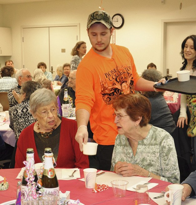 Volunteer Derek Crain serves food to Helen Thompson and Ruth Garrett during a New Year's celebration lunch at the Auburn Senior Activity Center last Friday.