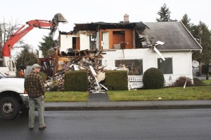 Auburn’s Rod Cartwright observes as crews dismantle the family’s home that had spanned four generations but had fallen in disrepair.