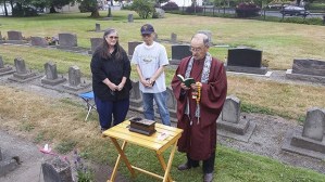 The Rev. Koshin Ogui reads as Nancy and Kenji Togami look on during a rededication of two graves – Kenji’s sisters Mihoko and Yoko – in Pioneer Cemetery on July 9.