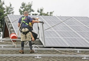 Workers from Forecast Solar install solar panels atop the Sun Break Café on Tuesday.