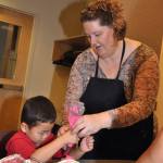 Laurie Pfalzer helps Minjoon Kim, 4, frost his cupcake during a creative holiday baking class at the Algona-Pacific Library on Monday. The program, presented by Pfalzer of Pastry Craft, taught parents and their children how to make buttercream frosting, create colors for decorating, use pastry bags and other baking tips. RACHEL CIAMPI, Auburn Reporter