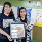 Lori Sheehan, a teacher at Lake View Elementary School, shows off a custom piece of artwork Nadia Diaz designed and drew illustrating an animal that most reminded her of her autistic brother, Brandon. Diaz chose a chameleon and drew multi-colored autism awareness puzzle pieces into the body. COURTESY PHOTO, Heidi Baumgartner